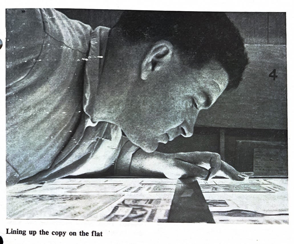 Close-up of a man leaning over a lightbox looking at photographs